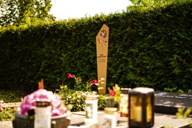 Aluminium Grabstele in Gold mit Rosenmotiv vor Hecke